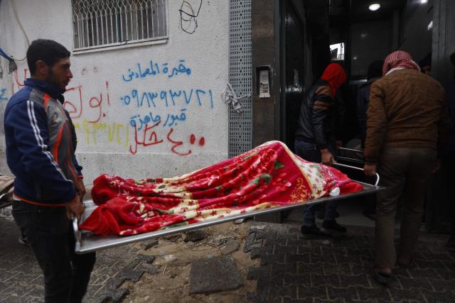 Palestinians carry a body during the funeral of three displaced members of the Hamoda family who died after parts of a war-damaged building where they had taken shelter collapsed on a windy winter day in Gaza City on January 13, 2026. A fragile ceasefire has been in place since October, following a deadly war waged by Israel in response to Hamas's unprecedented October 7, 2023 attack on Israel. Nearly 80 percent of buildings in Gaza have been destroyed or damaged by the war, according to UN data. (Photo by Omar AL-QATTAA / AFP)