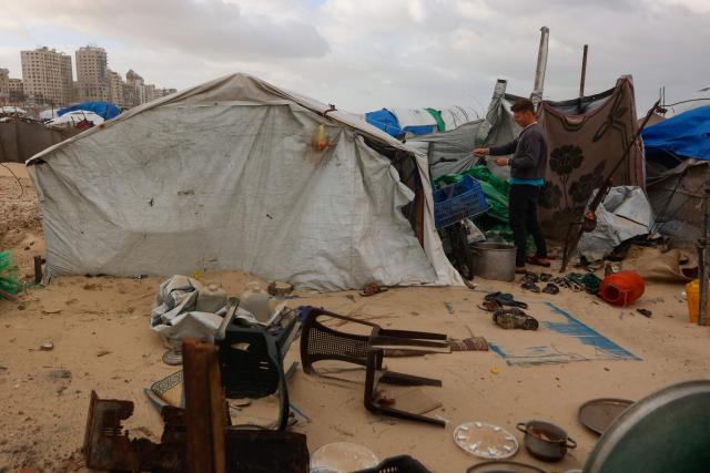 A displaced Palestinian man fixes a tent shelter set up along the shore in Gaza City as strong winter winds sweep the Palestinian enclave on January 13, 2026. A fragile ceasefire has been in place since October, following a deadly war waged by Israel in response to Hamas's unprecedented October 7, 2023 attack on Israel. Nearly 80 percent of buildings in Gaza have been destroyed or damaged by the war, according to UN data. (Photo by Omar AL-QATTAA / AFP)