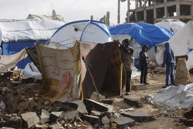 A displaced Palestinian man fixes a tent shelter set up along the shore in Gaza City as strong winter winds sweep the Palestinian enclave on January 13, 2026. A fragile ceasefire has been in place since October, following a deadly war waged by Israel in response to Hamas's unprecedented October 7, 2023 attack on Israel. Nearly 80 percent of buildings in Gaza have been destroyed or damaged by the war, according to UN data. (Photo by Omar AL-QATTAA / AFP)