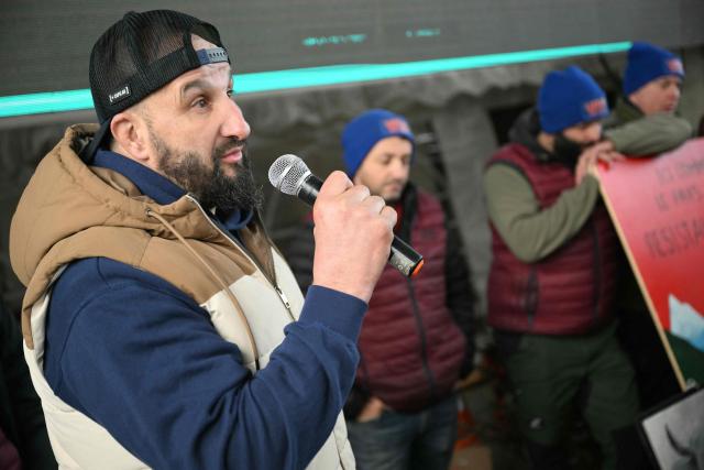Farmers listen to their leader Jerome Bayle (L) during a farmers blockade on the A64 motorway to protest against the government's mandatory culling protocol for cattle herds affected by lumpy skin disease (dermatose nodulaire contagieuse) and the EU-Mercosur trade deal, in Carbonne, southwestern France on January 13, 2026. Farmers of so-called "Ultras de l'A64" group, who have been occupying a roadblock on the A64 Toulouse-Bayonne motorway in Carbonne for a month, announced on January 13, 2026 that they would be "lifting the roadblock", following negociations with the prefect. Law enforcement had been deployed to the site in the early hours of the morning. (Photo by Lionel BONAVENTURE / AFP)