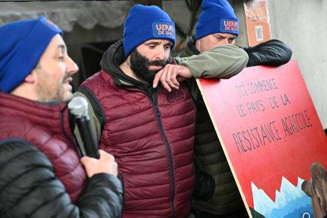 Farmers listen to their leader Jerome Bayle (unseen) during a farmers blockade on the A64 motorway to protest against the government's mandatory culling protocol for cattle herds affected by lumpy skin disease (dermatose nodulaire contagieuse) and the EU-Mercosur trade deal, in Carbonne, southwestern France on January 13, 2026. Farmers of so-called "Ultras de l'A64" group, who have been occupying a roadblock on the A64 Toulouse-Bayonne motorway in Carbonne for a month, announced on January 13, 2026 that they would be "lifting the roadblock", following negociations with the prefect. Law enforcement had been deployed to the site in the early hours of the morning. (Photo by Lionel BONAVENTURE / AFP)