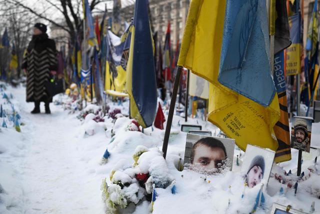 A woman visits the snow-covered memorial for the fallen Ukrainian and foreign fighters on Independence Square in Kyiv on January 13, 2026, amid the Russian invasion of Ukraine. (Photo by Sergei GAPON / AFP)