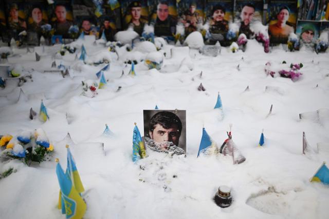 This photograph taken on January 13, 2026 shows portraits of fallen Ukrainian and foreign fighters covered with snow at the memorial on Independence Square in Kyiv, amid the Russian invasion of Ukraine. (Photo by Sergei GAPON / AFP)