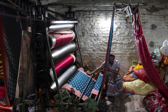 A worker smoothens out Banarasi sarees at a workshop in Varanasi on January 13, 2026. (Photo by Niharika KULKARNI / AFP)