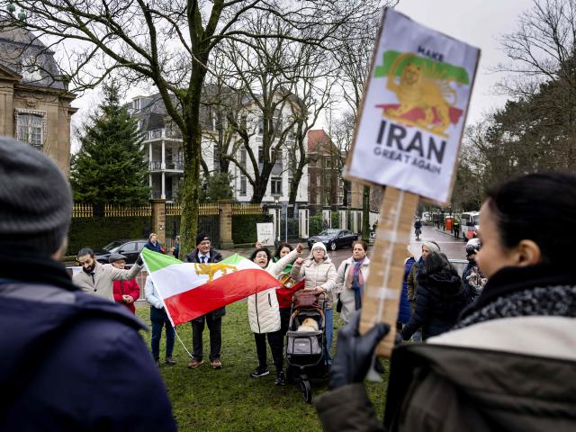 Protesters hold a Lion and Sun flag, the Iranian flag prior to the 1979 Islamic revolution, during a demonstration outside the Iranian embassy in The Hague, on January 13, 2026. A violent crackdown on a wave of protests in Iran has killed at least 648 people, Norway-based NGO Iran Human Rights (IHR) said on January  12, as Iranian authorities sought to regain control of the streets with mass nationwide rallies. The demonstrations moved from protesting economic grievances to demanding a wholesale change from the clerical system that has ruled Iran since the 1979 revolution that ousted the shah. (Photo by Sem van der Wal / ANP / AFP) / Netherlands OUT