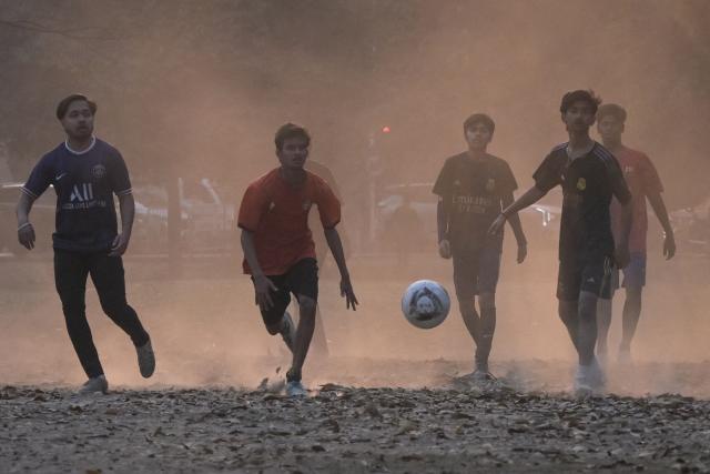 Boys play football on a dusty winter afternoon in Kolkata on January 13, 2026. (Photo by Dibyangshu SARKAR / AFP)