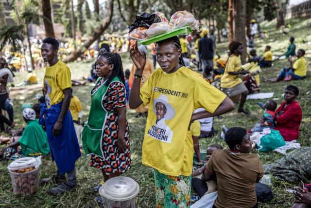 A street vendor looks for costumers as supporters of Uganda’s incumbent president and National Resistance Movement (NRM) presidential candidate Yoweri Museveni gather to enter the rally grounds ahead of the party’s closing campaign rally ahead of the 2026 Ugandan general elections, in Kampala on January 13, 2026. (Photo by AFP)