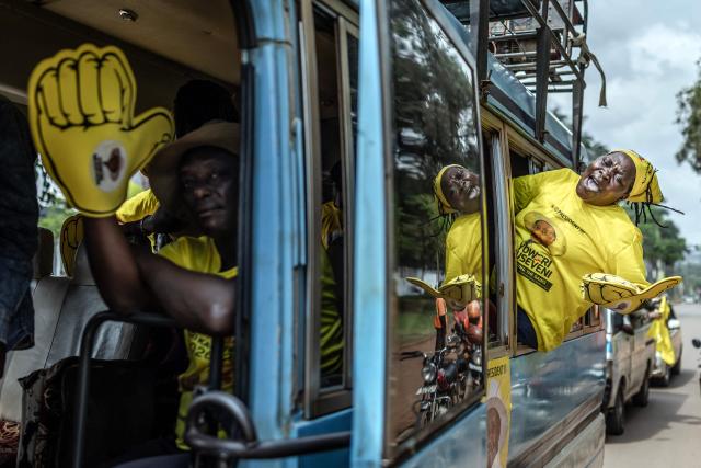 TOPSHOT - Supporters of Uganda’s incumbent president and National Resistance Movement (NRM) presidential candidate Yoweri Museveni chant slogans from a bus as they head to the rally grounds ahead of the party’s closing campaign rally ahead of the 2026 Ugandan general elections, in Kampala on January 13, 2026. (Photo by AFP)
