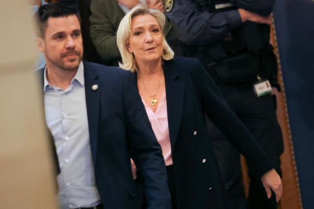 President of the parliamentary group of the French far-right Rassemblement National (RN) party, Marine Le Pen (R) leaves the courtroom on the first day of a hearing in her appeal trial on suspicion of embezzlement of European public funds, at Paris courthouse, on January 13, 2026. The appeal comes after a court last year barred the President of the RN parliamentary group Marine Le Pen from running for office for five years over a European Parliament fake-jobs scam involving her and other officials from her National Rally party. The hearing is expected to run until February 11, 2026, with a decision expected this summer. Twelve of the accused, as well as the far-right party itself, have appealed against the verdict while another 12 people -- including one of Le Pen's sisters -- have decided to accept their convictions without appealing. (Photo by Thomas SAMSON / AFP)