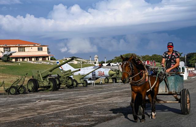 A man rides in a horse-drawn carriage next to an exhibition of Soviet-era weapons at the Fortress of San Carlos de la Cabana in Havana on January 13, 2026. (Photo by YAMIL LAGE / AFP)