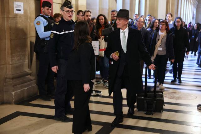 Former French Member of European Parliament and former ;ember of the Front National far-right party Fernand Le Rachinel arrives at the courtroom on the first day of a hearing in her appeal trial on suspicion of embezzlement of European public funds, at Paris courthouse, on January 13, 2026. The appeal comes after a court last year barred the President of the RN parliamentary group Marine Le Pen from running for office for five years over a European Parliament fake-jobs scam involving her and other officials from her National Rally party. The hearing is expected to run until February 11, 2026, with a decision expected this summer. Twelve of the accused, as well as the far-right party itself, have appealed against the verdict while another 12 people -- including one of Le Pen's sisters -- have decided to accept their convictions without appealing. (Photo by Thomas SAMSON / AFP)