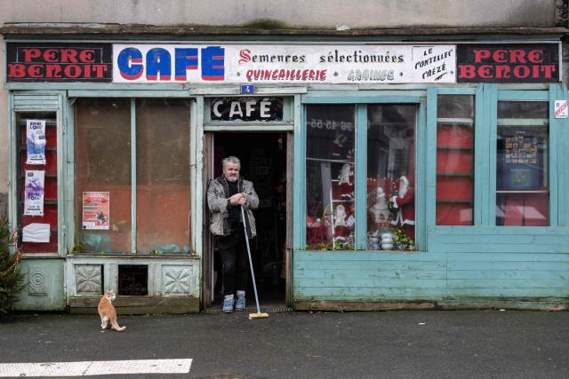 French bar owner Paul Le Contellec, also known as Paulo, poses at his cafe-bazaar, opened in 1949 by his grand-parents in Callac, western France, on December 16, 2025. France's President argued on January 5, 2026 for the inclusion of French bistros and cafes in UNESCO's intangible cultural heritage, alongside the baguette. The French Bistros and Cafes Association launched an initiative in 2024 to have these convivial places listed as UNESCO World Heritage sites. "The bistros and cafes of France are keepers of time. They cross centuries and intersect generations," it emphasizes on its website. (Photo by Fred TANNEAU / AFP)