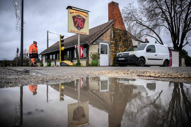 A worker walks past the Table 76 bar and restaurant in Vignoux-sur-Barangeon, central France, on January 8, 2026. France's President argued on January 5, 2026 for the inclusion of French bistros and cafes in UNESCO's intangible cultural heritage, alongside the baguette. The French Bistros and Cafes Association launched an initiative in 2024 to have these convivial places listed as UNESCO World Heritage sites. "The bistros and cafes of France are keepers of time. They cross centuries and intersect generations," it emphasizes on its website. (Photo by Loic VENANCE / AFP)