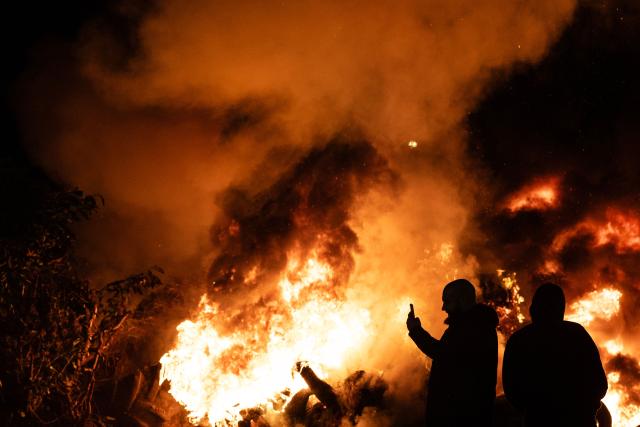 TOPSHOT - Farmers stand next to a fire on a roundabout in Quimper, western of France on January 13, 2026 during a farmers' blockade to protest against the government's mandatory culling protocol for cattle herds affected by lumpy skin disease (dermatose nodulaire contagieuse) and the EU-Mercosur trade deal. (Photo by Fred TANNEAU / AFP)