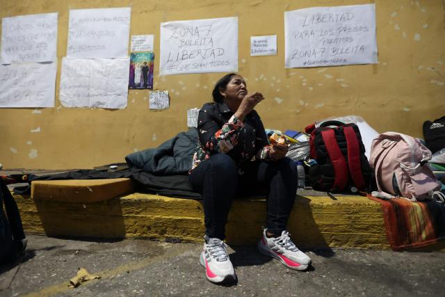 A woman eats a fruit during a vigil to demand freedom for political prisoners at El Helicoide -a facility and prison owned by the Venezuelan government and used for both regular and political prisoners of the Bolivarian National Intelligence Service (SEBIN)- in Caracas on January 13, 2026. Venezuela said on January 12, it had freed dozens more political prisoners as rights groups questioned the numbers and family members clamored for speedier releases after the US military ouster of long-term autocrat Nicolas Maduro. (Photo by Pedro MATTEY / AFP)