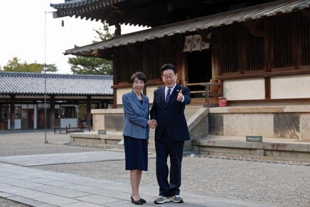 Japan's Prime Minister Sanae Takaichi (L) and South Korea's President Lee Jae Myung shake hands as they pose for photos during their visit to the Western Precinct (Saiin Garan) at the Horyu-ji Temple in Ikaruga, Nara prefecture on January 14, 2026. (Photo by Franck ROBICHON / POOL / AFP)