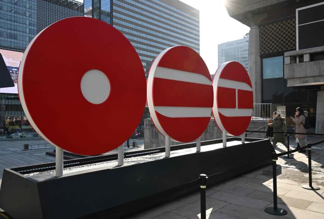 Pedestrians walk past the logo of BTS' 2026 album at Gwanghwamun Square in Seoul on January 14, 2026. K-pop megastars BTS will launch a comeback world tour from April, the band's label said on January 14. (Photo by Jung Yeon-je / AFP)