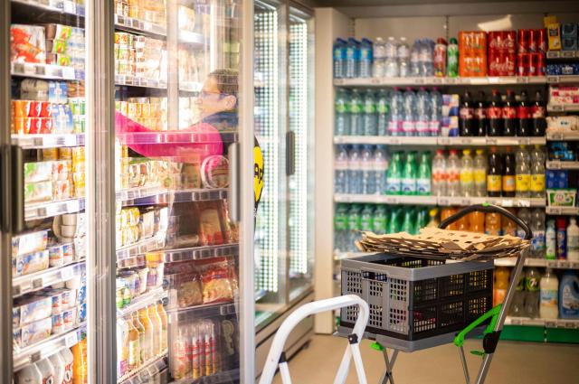 (FILES) Api company employee displays products in a self-service supermarket without a cashier set up in a 40m2 wooden mobile home in Claix, western France, on December 1, 2022. The Api company, which plans to install 40 new self-service convenience stores in the region by 2023, was founded two years ago by Julien Nau and Alex Grammatico who are local residents and who discovered a similar concept in Sweden. (Photo by YOHAN BONNET / AFP)