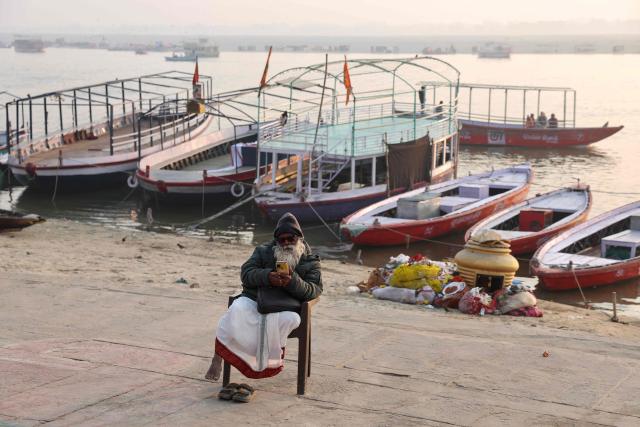 A man uses a mobile phone along the banks of river Ganges at Kshemeshwar Ghat in Varanasi on January 14, 2026. (Photo by Niharika KULKARNI / AFP)