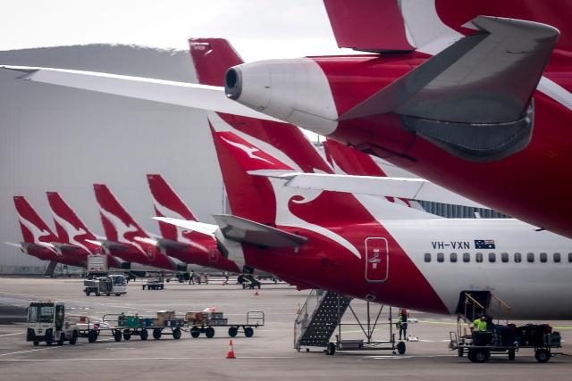 Qantas Airways ground staff are seen on the tarmac near planes at the domestic terminal of Sydney International Airport in Sydney on January 14, 2026. (Photo by DAVID GRAY / AFP)