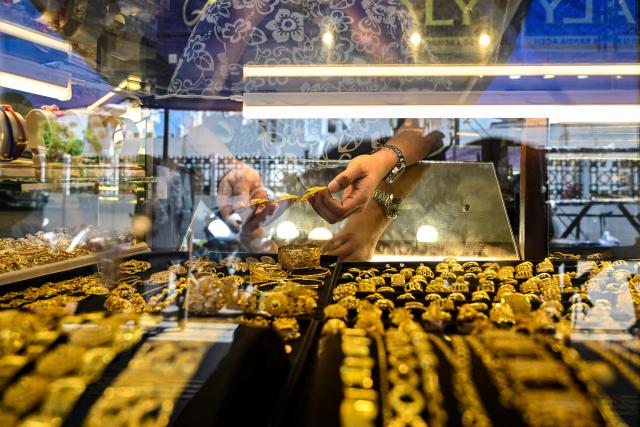 An employee holds pieces of gold jewellery at a jewellery store in Banda Aceh on January 14, 2026. (Photo by CHAIDEER MAHYUDDIN / AFP)