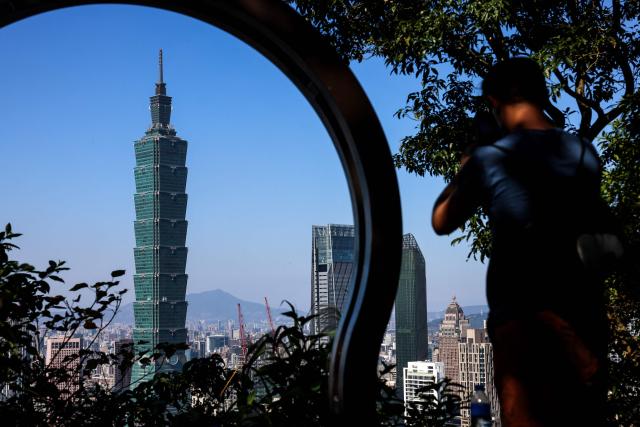 A person takes pictures of the landmark Taipei 101 building in Taipei on January 14, 2026. (Photo by I-Hwa Cheng / AFP)