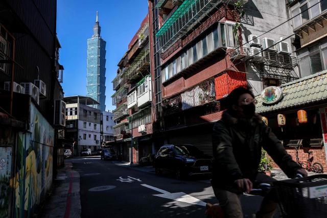 A cyclist rides past as the landmark Taipei 101 building is seen in the background in Taipei on January 14, 2026. (Photo by I-Hwa Cheng / AFP)