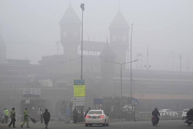 Commuters drive past the Lahore railway station shrouded in dense fog in Lahore on January 14, 2026. (Photo by Arif ALI / AFP)