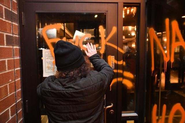 Anti-ICE demonstrators protest outside the graffiti tagged Graduate Hotel where federal immigration agents are believed to be staying in Minneapolis, Minnesota on January 13, 2026. Hundreds more federal agents were heading to Minneapolis, the US homeland security chief said on January 11, brushing aside demands by the Midwestern city's Democratic leaders to leave after an immigration officer fatally shot a woman protester. In multiple TV interviews, US Homeland Secretary Kristi Noem defended the actions of the officer who shot and killed 37-year-old Renee Nicole Good, whose death has sparked renewed protests nationwide against President Donald Trump's immigration crackdown. (Photo by Octavio JONES / AFP)