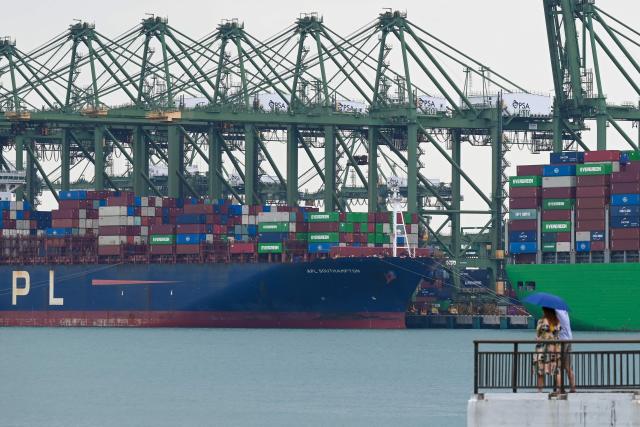 A couple looks on as a container vessel is docked at Pasir Panjang terminal port in Singapore on January 14, 2026. (Photo by Roslan RAHMAN / AFP)