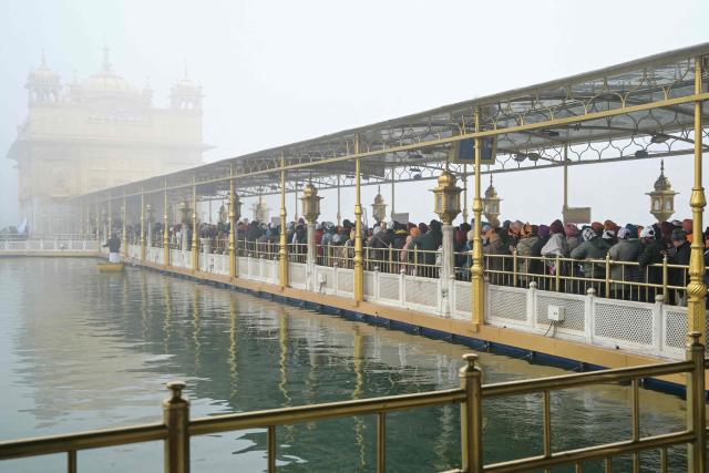 Sikh devotees pay their respects at the Golden Temple on the occasion of Maghi festival or Makar Sankranti, amid dense fog in Amritsar on January 14, 2026. (Photo by Narinder NANU / AFP)