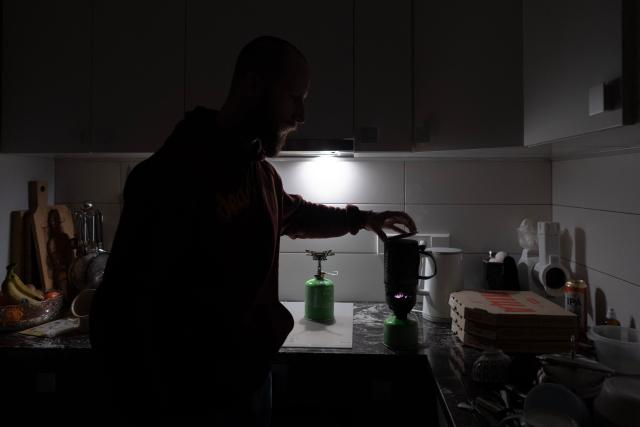 Local resident Stas prepares tea using a gas burner during a power outage at the family's apartment in Kyiv on January 13, 2026, amid the Russian invasion of Ukraine. (Photo by Andrew Kravchenko / AFP)