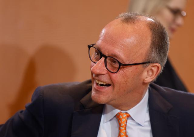 German Chancellor Friedrich Merzlaughs as he starts the weekly cabinet meeting on January 14, 2026 at the Chancellery in Berlin. (Photo by Odd ANDERSEN / AFP)