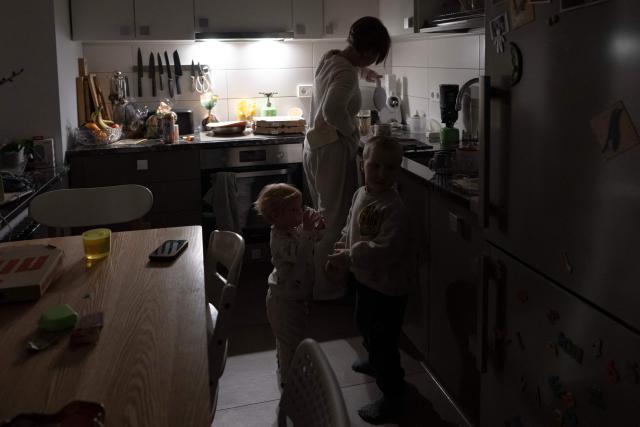 Local residents Kateryna and her children spend time together during a power outage at the family's apartment in Kyiv on January 13, 2026, amid the Russian invasion of Ukraine. (Photo by Andrew Kravchenko / AFP)