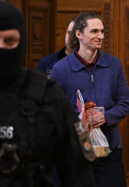 The defendant, German anti-fascist activist Maja T, is lead into the courtroom by officials in Budapest on January 14, 2026 to expect his verdict for allegedly participating in attacks against presumed neo-Nazis on the streets of the Hungarian capital. The case sparked uproar in Germany, with the country's top court saying the extradition order for the suspect, who identifies as non-binary, had failed to take into account potentially dangerous prison conditions in Hungary, especially for LGBTQ people. The defendant is accused of four counts of attempted assault as part of a criminal organisation aiming to "send a deterrent message to members of extreme-right movements" by "inflicting various life-threatening injuries" according to a court statement. (Photo by Attila KISBENEDEK / AFP) / EDITORS NOTE: ACCORDING TO COURT'S RULING THE FACES OF THE JUSTICE OFFICERS AND POLICE IN THE COURTROOM MUST BE MADE UNRECOGNIZABLE