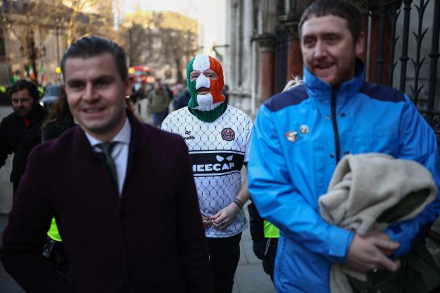 (L to R) Belfast-based lawyer Darragh Mackin, Kneecap member DJ Provaí and Kneecap manager Dan Lambert arrive outside the Royal Courts of Justice ahead of the arrival of band member Liam O'Hanna, who performs under the stage name Mo Chara, in London on January 14, 2026. The singer Mo Chara is back before the courts on January 14 as British prosecutors challenge a decision to drop a terrorism charge against him. (Photo by Henry NICHOLLS / AFP)