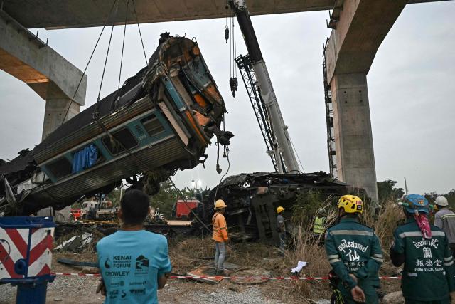 Recovery workers watch as a carriage of a train that crashed when a construction crane collapsed is lifted off the tracks in Thailand's Nakhon Ratchasima province on January 14, 2026. A crane at a China-backed high-speed rail project in Thailand collapsed onto a passenger train on January 14 and caused it to derail, killing at least 28 people and injuring dozens more, authorities said. (Photo by Lillian SUWANRUMPHA / AFP)
