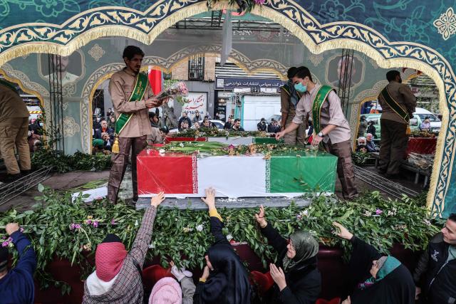 Iranians mourn during the funerals of security forces personnel killed in recent protests in Tehran on January 14, 2026. A funeral ceremony began in Tehran on January 14, 2026 for over 100 members of the security forces and other "martyrs" killed in the wave of protests that has rocked the Islamic republic, state television said. (Photo by ATTA KENARE / AFP)