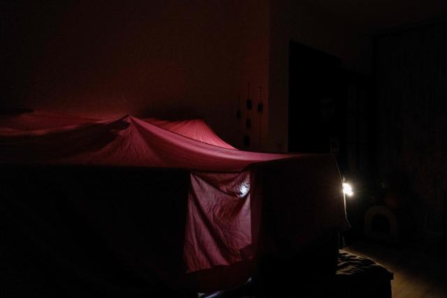 A photograph taken in the evening of January 13, 2026, shows a tent built up inside the home of local resident an piano teacher Evgenia, and made of pillows and blankets in order to warm up, during a blackout in Kyiv, amid the Russian invasion of Ukraine. (Photo by Tetiana DZHAFAROVA / AFP)