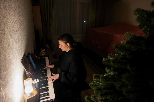 Local resident an piano teacher Evgenia plays the piano with a flashlight in her apartment, during a blackout in Kyiv, in the evening of January 13, 2026, amid the Russian invasion of Ukraine. (Photo by Tetiana DZHAFAROVA / AFP)