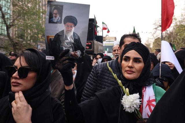 TOPSHOT - An Iranian woman holds a portrait of Iran’s Supreme Leader Ayatollah Ali Khamenei during the funerals of security forces personnel killed in recent protests in Tehran on January 14, 2026. A funeral ceremony began in Tehran on January 14, 2026 for over 100 members of the security forces and other "martyrs" killed in the wave of protests that has rocked the Islamic republic, state television said. (Photo by ATTA KENARE / AFP)