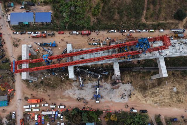 An aerial view of the wreckage of a train that crashed when a construction crane collapsed in Thailand's Nakhon Ratchasima province on January 14, 2026. A crane at a China-backed high-speed rail project in Thailand collapsed onto a passenger train on January 14 and caused it to derail, killing at least 32 people, authorities said. (Photo by Lillian SUWANRUMPHA / AFP)