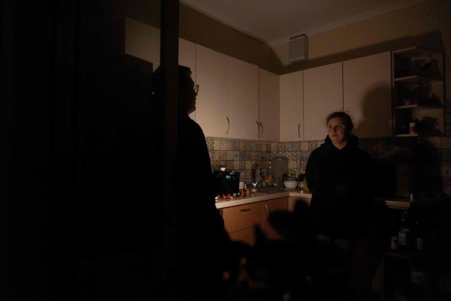 Local residents Evgenia with her husband Pavlo speak in the kitchen with a flashlight, during a blackout in Kyiv, in the evening of January 13, 2026, amid the Russian invasion of Ukraine. (Photo by Tetiana DZHAFAROVA / AFP)