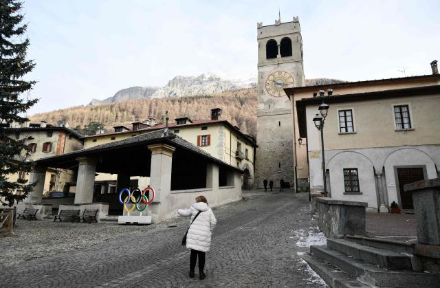 A woman gestures next to Olympic rings in the main square of Bormio which will host all the alpine men's skiing events as part of the Milano Cortina 2026 Olympics, on January 14, 2026. (Photo by Stefano RELLANDINI / AFP)