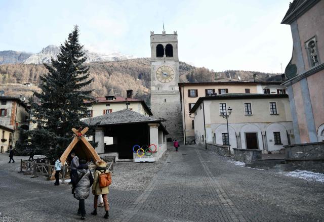 People stroll past Olympic rings in the main square of Bormio which will host all the alpine men's skiing events as part of the Milano Cortina 2026 Olympics, on January 14, 2026. (Photo by Stefano RELLANDINI / AFP)