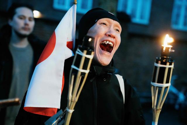 A protestor with a Greenlandic flag holds torch lights during a demonstration under the motto "Greenland is for Greenlanders" in fromnt of the embassy in Copenhagen on January 14, 2026. Denmark will beef up its military presence in Greenland "from today", the defence ministry said, just before high-stakes talks were to start in Washington over US President Donald Trump's threats to take over the Arctic island. (Photo by Thomas Traasdahl / Ritzau Scanpix / AFP) / Denmark OUT