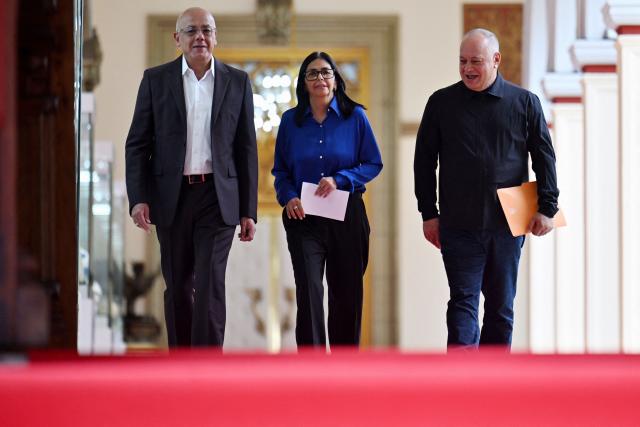 Venezuela's interim President Delcy Rodriguez (C), President of the National Assembly Jorge Rodriguez (L), and Minister of the Popular Power for Interior Diosdado Cabello walk in a hallway to arrive at a press conference at the Miraflores Presidential Palace in Caracas on January 14, 2026. Venezuela has freed 15 journalists, including a leading opposition figure, as the slow release of political prisoners begun after Nicolas Maduro's ouster continues, activists said on January 14. (Photo by Juan BARRETO / AFP)