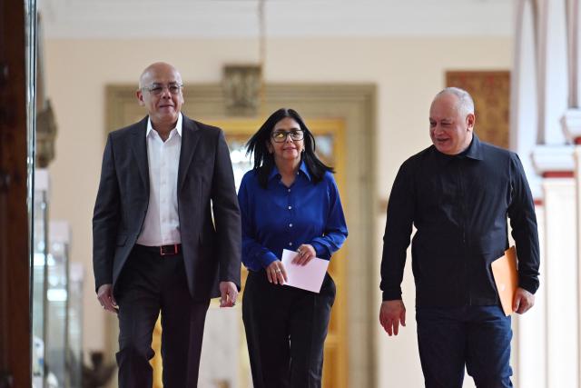 Venezuela's interim President Delcy Rodriguez (C), President of the National Assembly Jorge Rodriguez (L), and Minister of the Popular Power for Interior Diosdado Cabello walk in a hallway to arrive at a press conference at the Miraflores Presidential Palace in Caracas on January 14, 2026. Venezuela has freed 15 journalists, including a leading opposition figure, as the slow release of political prisoners begun after Nicolas Maduro's ouster continues, activists said on January 14. (Photo by Juan BARRETO / AFP)