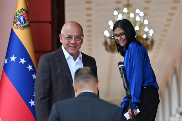 Venezuela's interim President Delcy Rodriguez (R) smiles next to President of the National Assembly Jorge Rodriguez after a press conference at the Miraflores Presidential Palace in Caracas on January 14, 2026. Venezuela's interim president Delcy Rodriguez said on january 14, that her country was looking to "a new political era" after the January 3 ouster of leader Nicolas Maduro in a US military strike. (Photo by Juan BARRETO / AFP)
