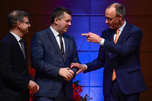 German Chancellor Friedrich Merz (R) gestures to Saxony-Anhalt's incoming State Premier Sven Schulze (C) as Sascha Glaesser (L), president of Halle's Chamber of Commerce and Industry looks on at the end of the New Year’s reception the Chamber of Commerce and Industry in Halle, eastern Germany on January 14, 2026. (Photo by John MACDOUGALL / AFP)